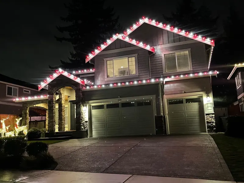 Craftsman home with red and warm white Candy Cane lights along the roofline and gables at night