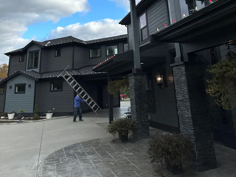 Installation day: a ladder set up beside a dark two-storey home while the lights go on