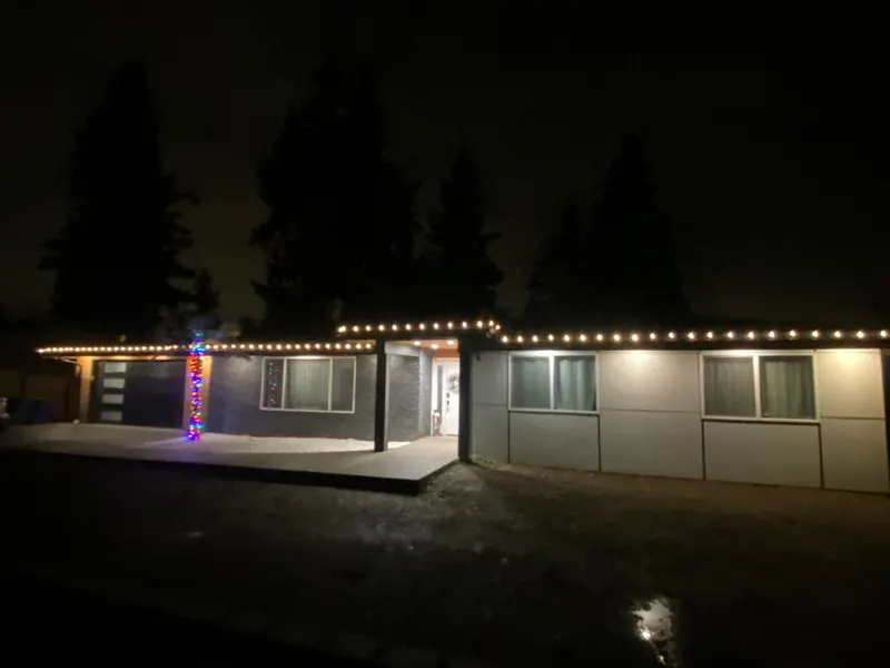 Single-storey home at night with a line of warm white lights along the front roof edge